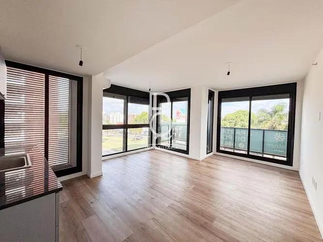 This image showcases a bright and modern open-concept living space, likely combining a living room and a partial kitchen area. The room features light wood-look flooring and white walls, creating a cl