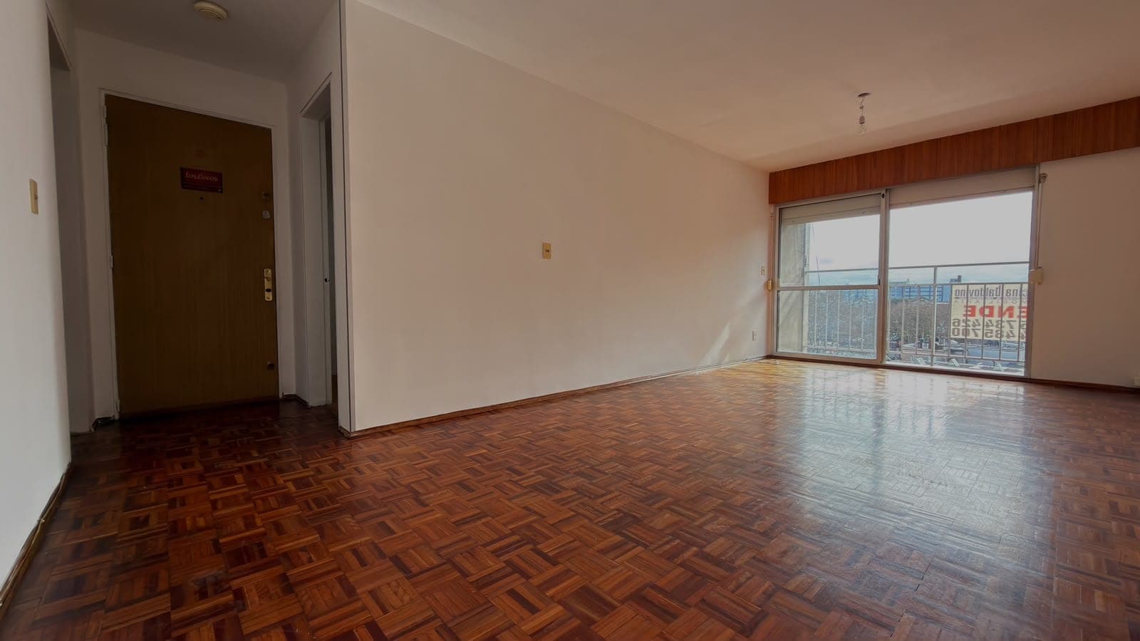 # Property Image Description
**Living Room/Main Living Space** - This spacious, well-lit room features beautiful herringbone parquet flooring in warm wood tones and clean white walls. Large sliding glass doors with a balcony provide excellent natural light and expansive city views, while the room's open layout and neutral décor create a modern, inviting atmosphere suitable for comfortable living.
