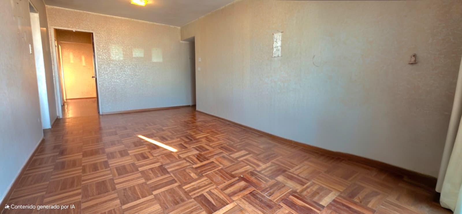 This is a spacious bedroom or living room with parquet wood flooring in a herringbone pattern and neutral beige walls in good condition. The room features natural light from a window, recessed ceiling lighting, and multiple doorways providing access to adjacent spaces. The space appears empty and ready for occupancy, with clean finishes and adequate electrical outlets visible on the walls.
WATERMARK: Contenido generado por IA