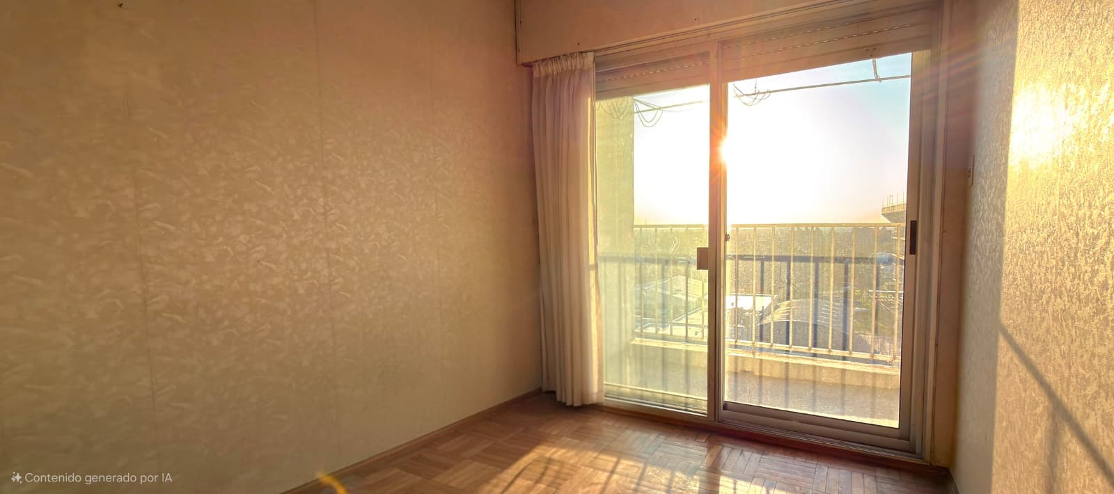 This is a bright bedroom or living space featuring warm, neutral-toned textured wallpaper and wooden flooring in good condition. The room is flooded with natural light from large sliding glass doors that open onto a spacious balcony with metal railings, offering expansive outdoor views. The space appears clean and well-maintained with simple cream-colored curtains framing the doors.
WATERMARK: Contenido generado por IA